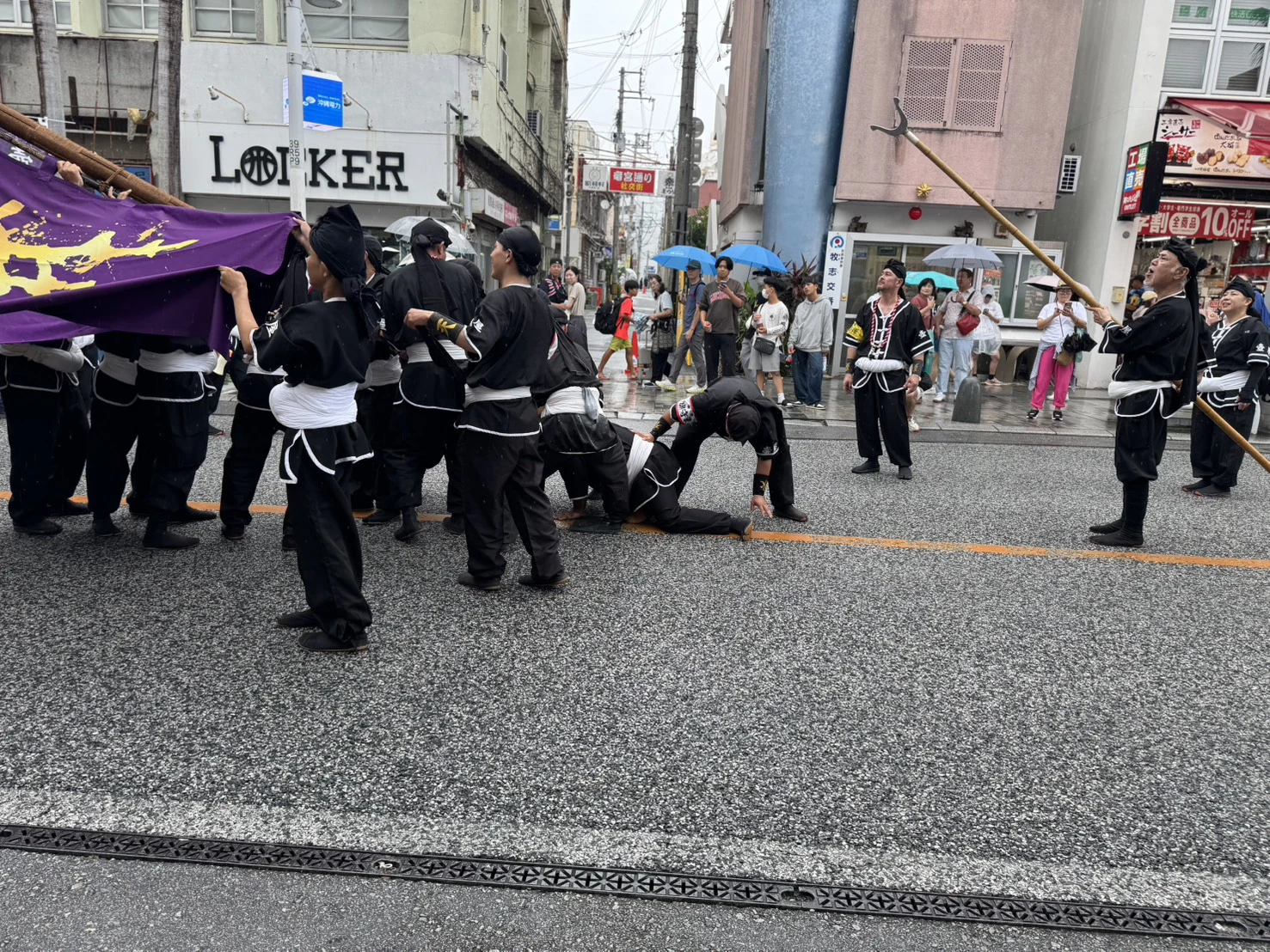低い位置の旗竿の周囲で、旗持ちと仲間が動きを合わせる場面