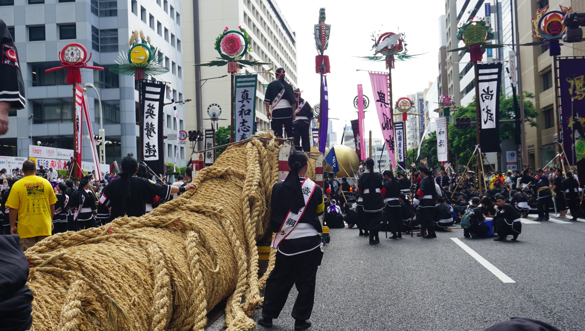 道路に置かれた那覇大綱挽の大綱と、その先に集まる旗頭